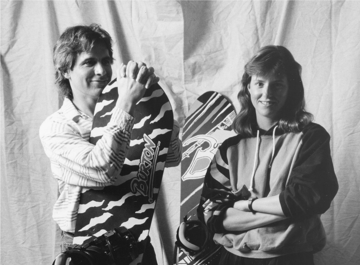 Jake Burton Carpenter and Donna posing with some Burton Safari Snowboards in the 1980s