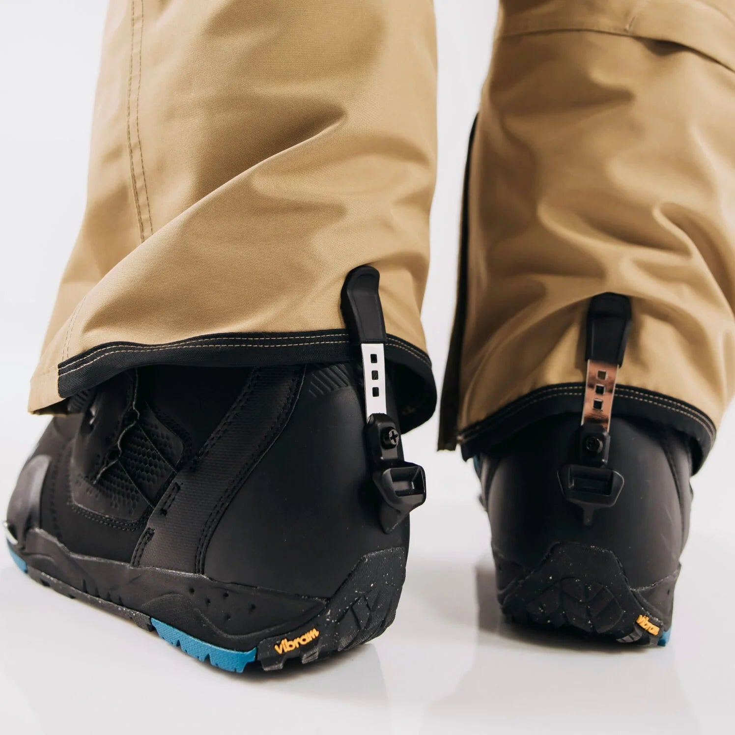 Close-up of cuff clip on black boots with beige pants on a white background