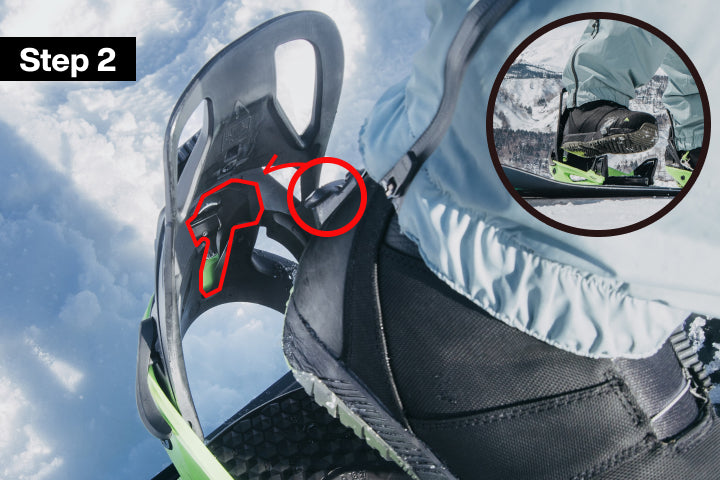 Instructional close-up showing a snowboard binding device with red highlighted areas and a circular inset demonstrating the fastened state, labeled 'Step 2' against a snowy outdoor background.