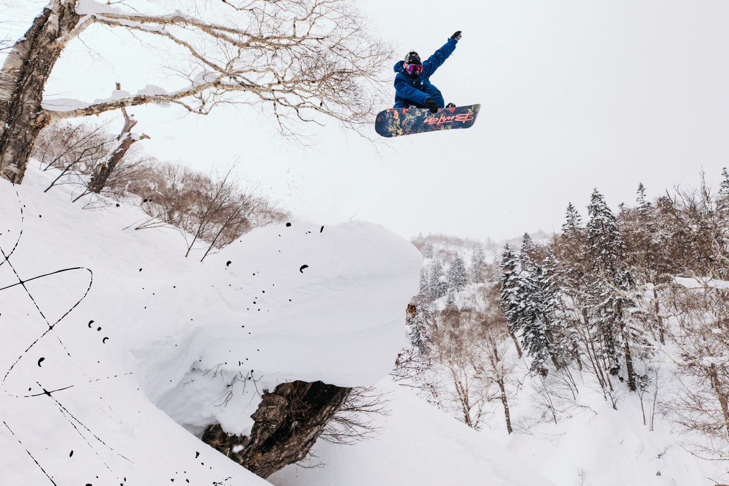 Snowboarder launches off a natural feature in the backcountry
