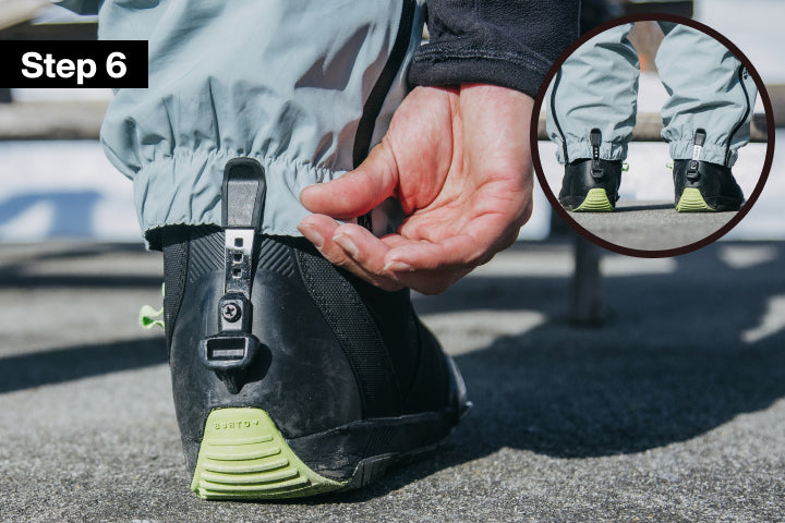 Close-up of a person tucking the cuff of their light gray snow pants under a silver boot clip. A circular inset shows the full lower legs wearing the setup, and a black 'Step 6' label appears in the top left.