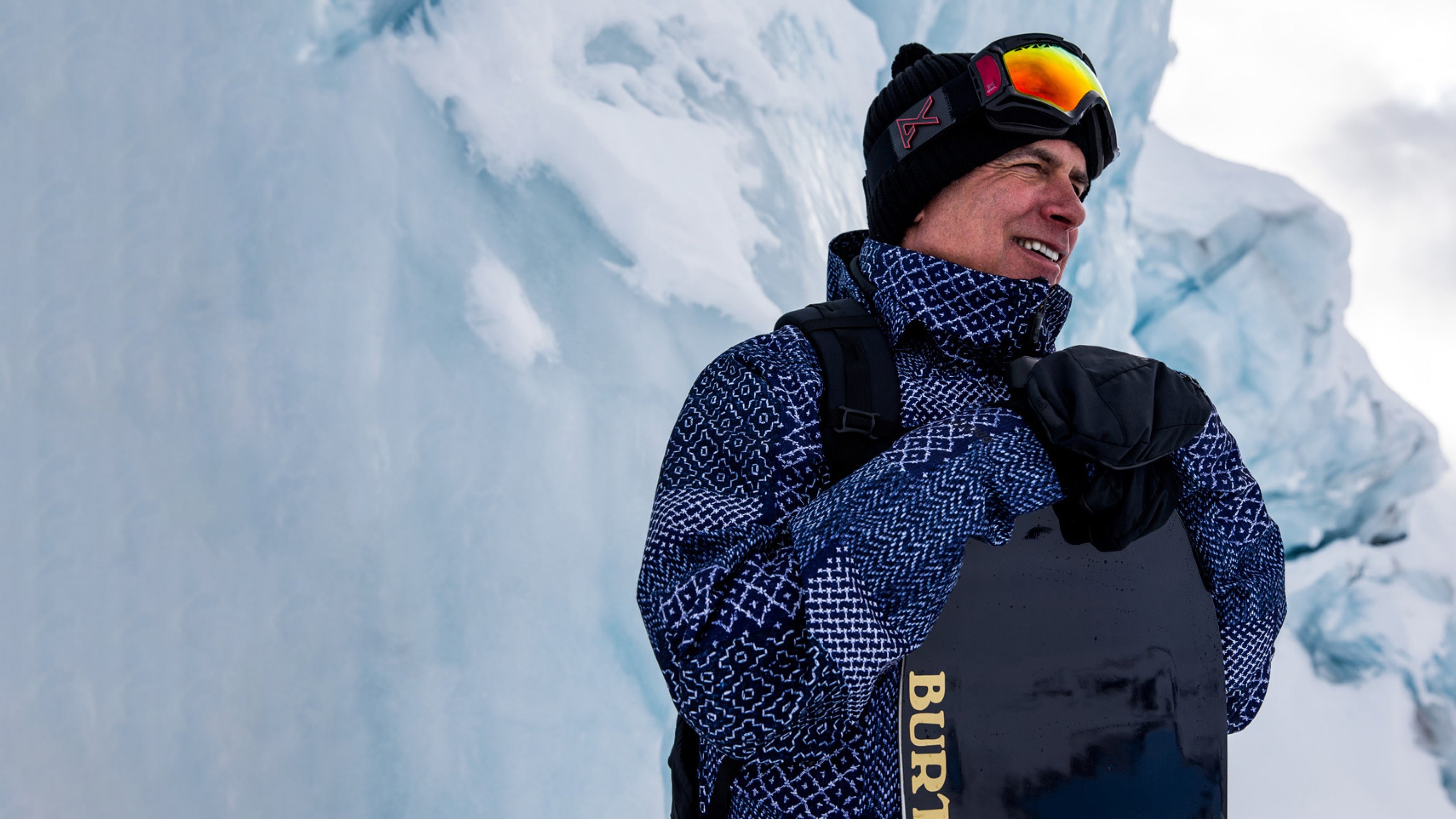 Jake Burton Carpenter on mountain holding a Burton snowboard